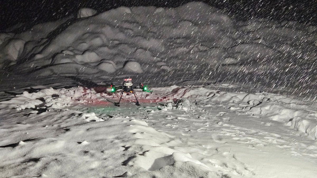 ロボットドローン実証：北海道・降雪の中、雪原でホバリングする寒冷地仕様の機体